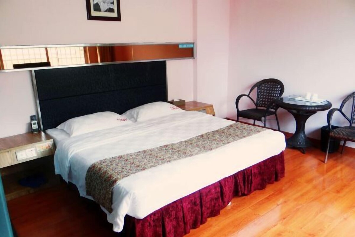 Quarto de hotel com uma cama, uma mesa pequena com cadeiras e uma mesa de cabeceira.