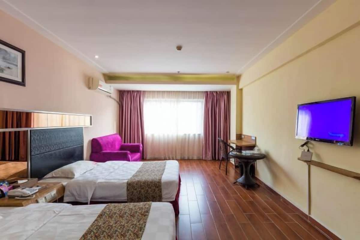 A hotel room with two beds, a television, a desk, and a chair.