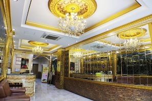 A luxurious lobby with marble flooring, a reception desk, and ornate gold detailing.