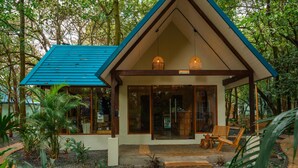 A small, two-story building with a blue roof and large windows, surrounded by lush greenery. - Selina River Venao (Las Escobas del Venado)