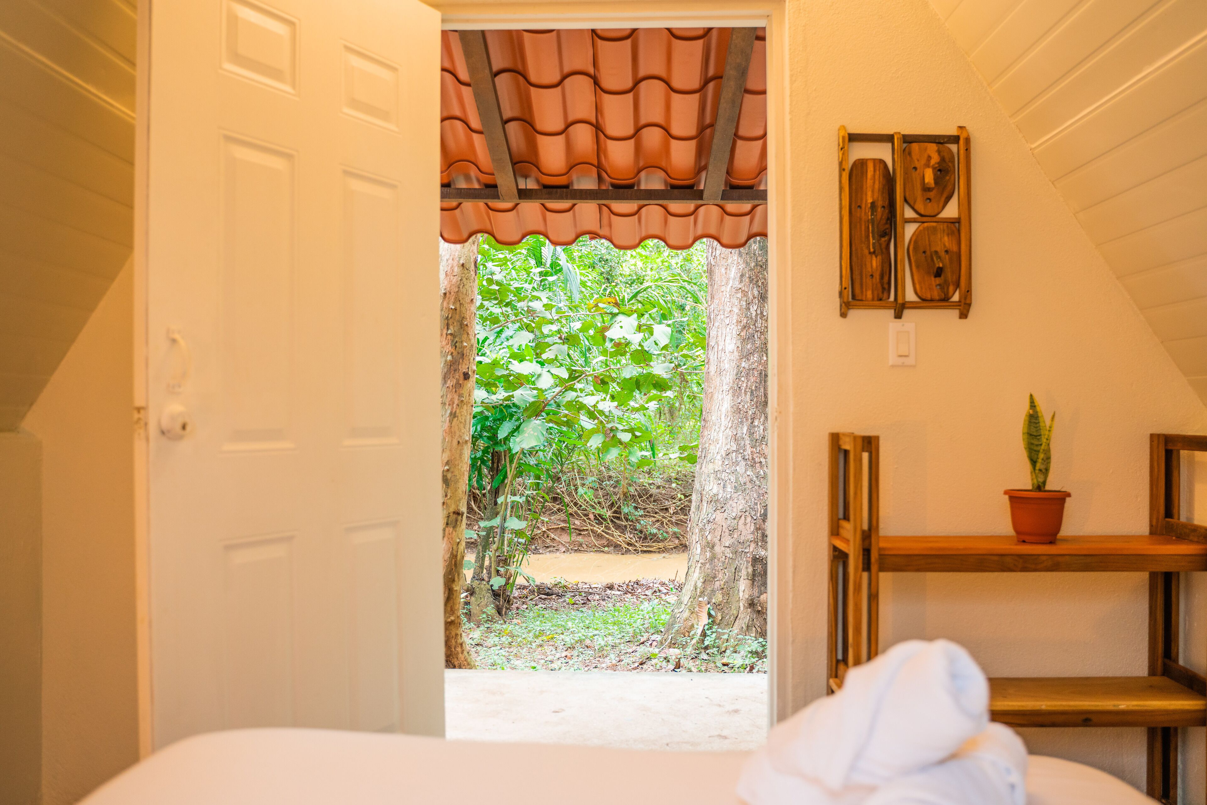 Ein Schlafzimmer mit Blick auf einen Garten, der durch eine Tür mit Ziegeldach sichtbar ist.