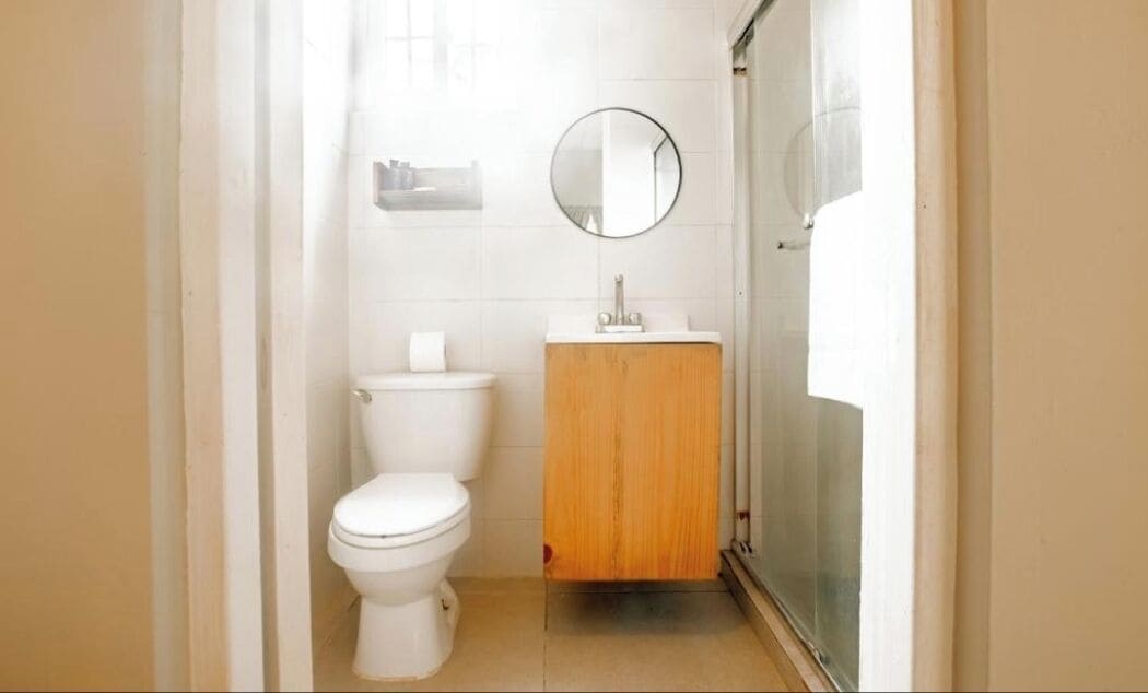A small, clean bathroom with a toilet, a wooden cabinet, and a mirror.