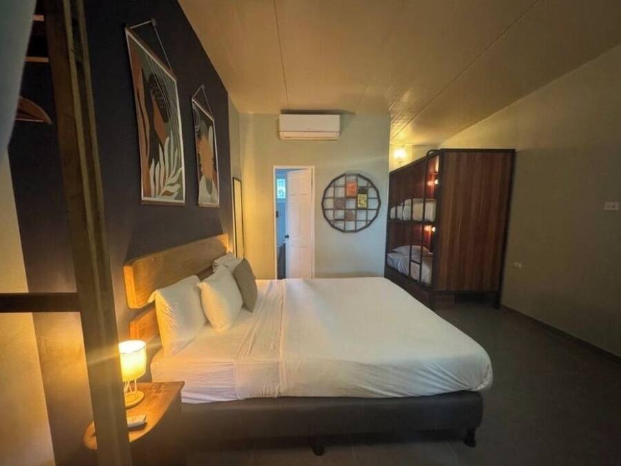 Une chambre d’hôtel avec un grand lit, une table de chevet avec une lampe, une armoire et des œuvres d’art murales.