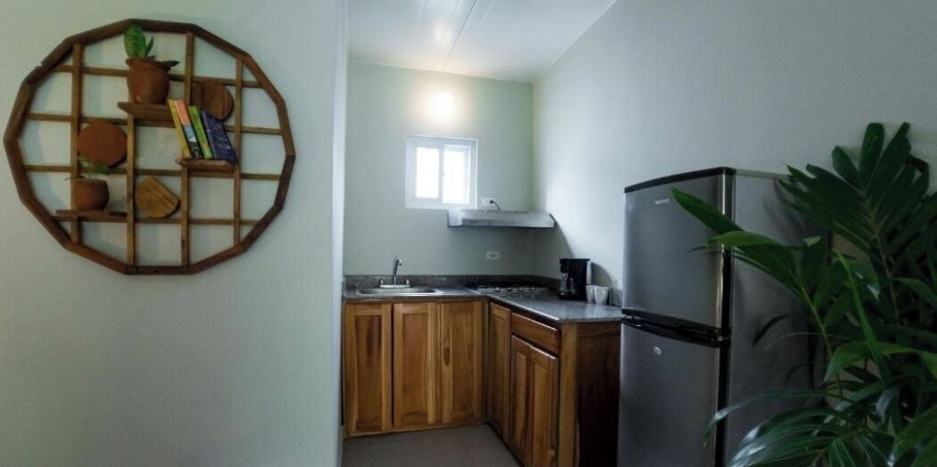 Una cocina compacta con armarios de madera, un refrigerador de acero inoxidable y una ventana sobre el fregadero.