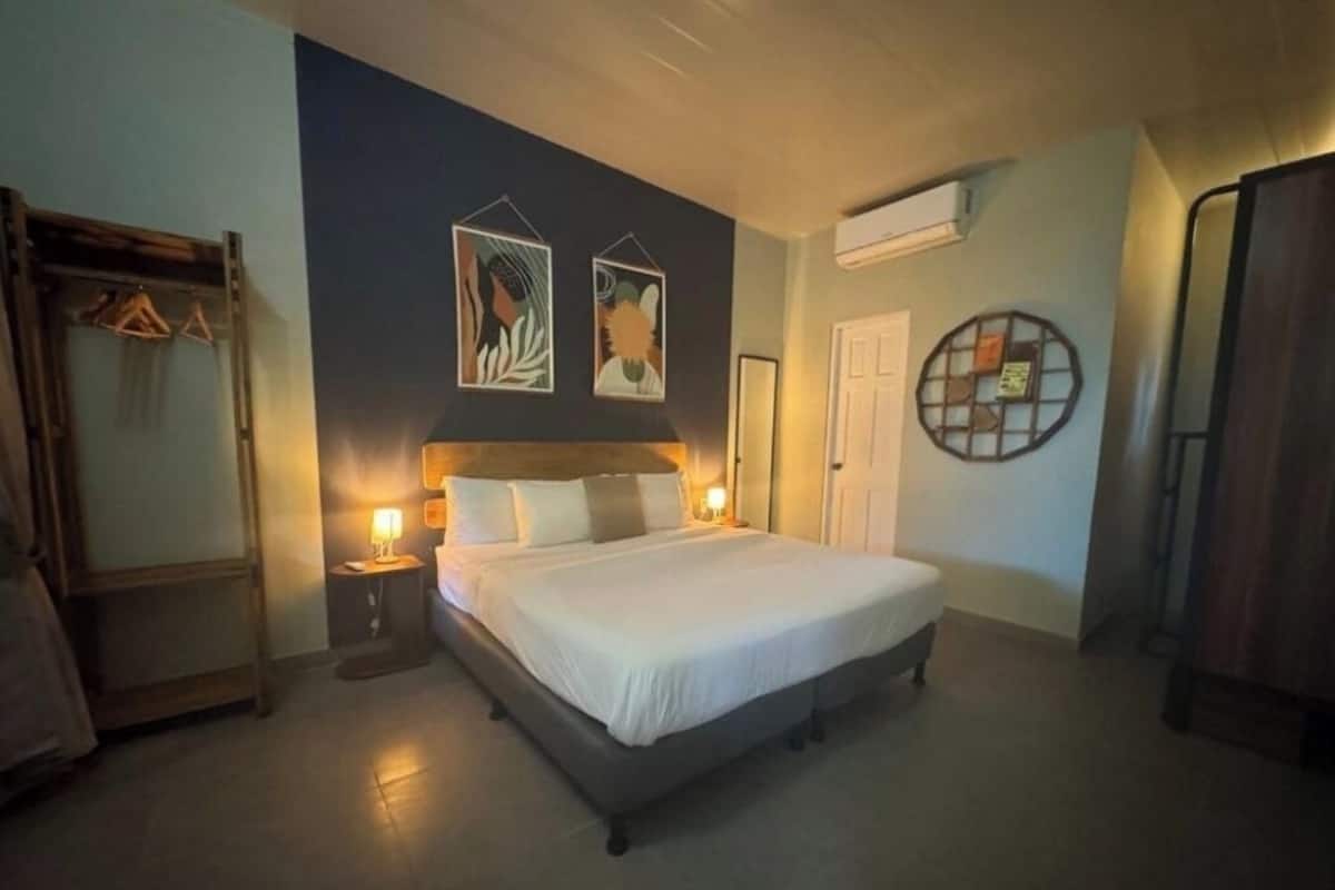 A bedroom with a large bed, bedside tables with lamps, a wardrobe, and artwork on the wall.