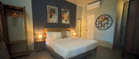 A bedroom with a large bed, bedside tables with lamps, a wardrobe, and artwork on the wall.