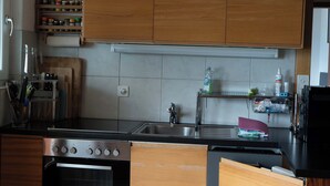 A modern kitchen with wooden cabinets, a stainless steel oven, and a black countertop.