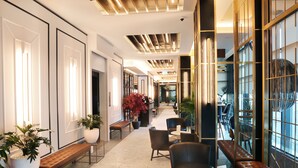 Un moderno vestíbulo de hotel con un largo pasillo, zonas de estar y grandes ventanales.