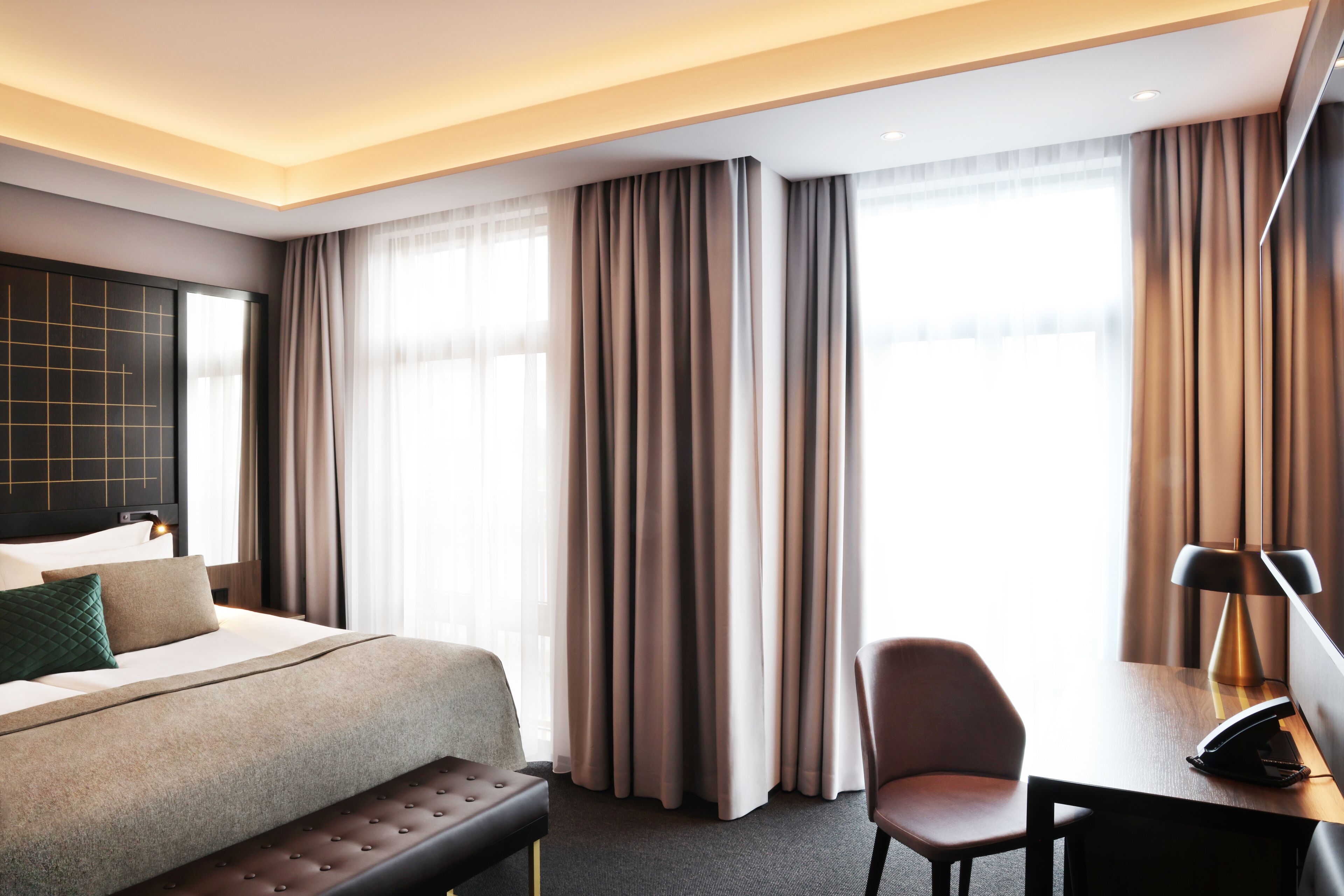 A modern hotel room with a large bed, a desk, and a chair.