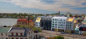 A waterfront cityscape with a mix of traditional and modern buildings, a clear sky, and a calm river. - Hotel Reykjavik Saga (Reykjavik)