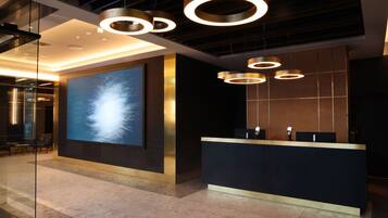 A modern reception area with a large digital screen, a reception desk, and circular pendant lighting.