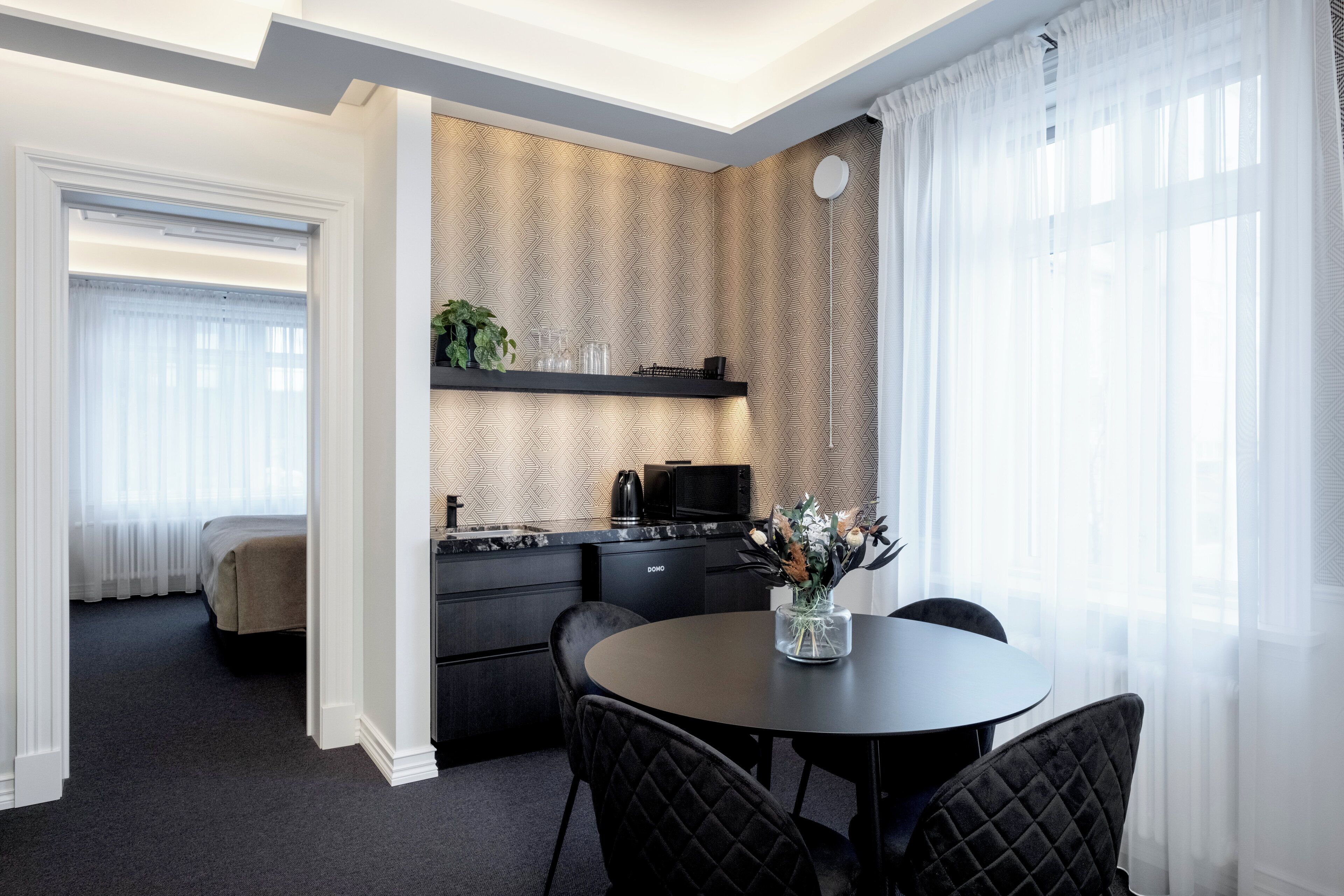Ein modernes Hotelzimmer mit Essbereich, einer Küche und einem Bett.