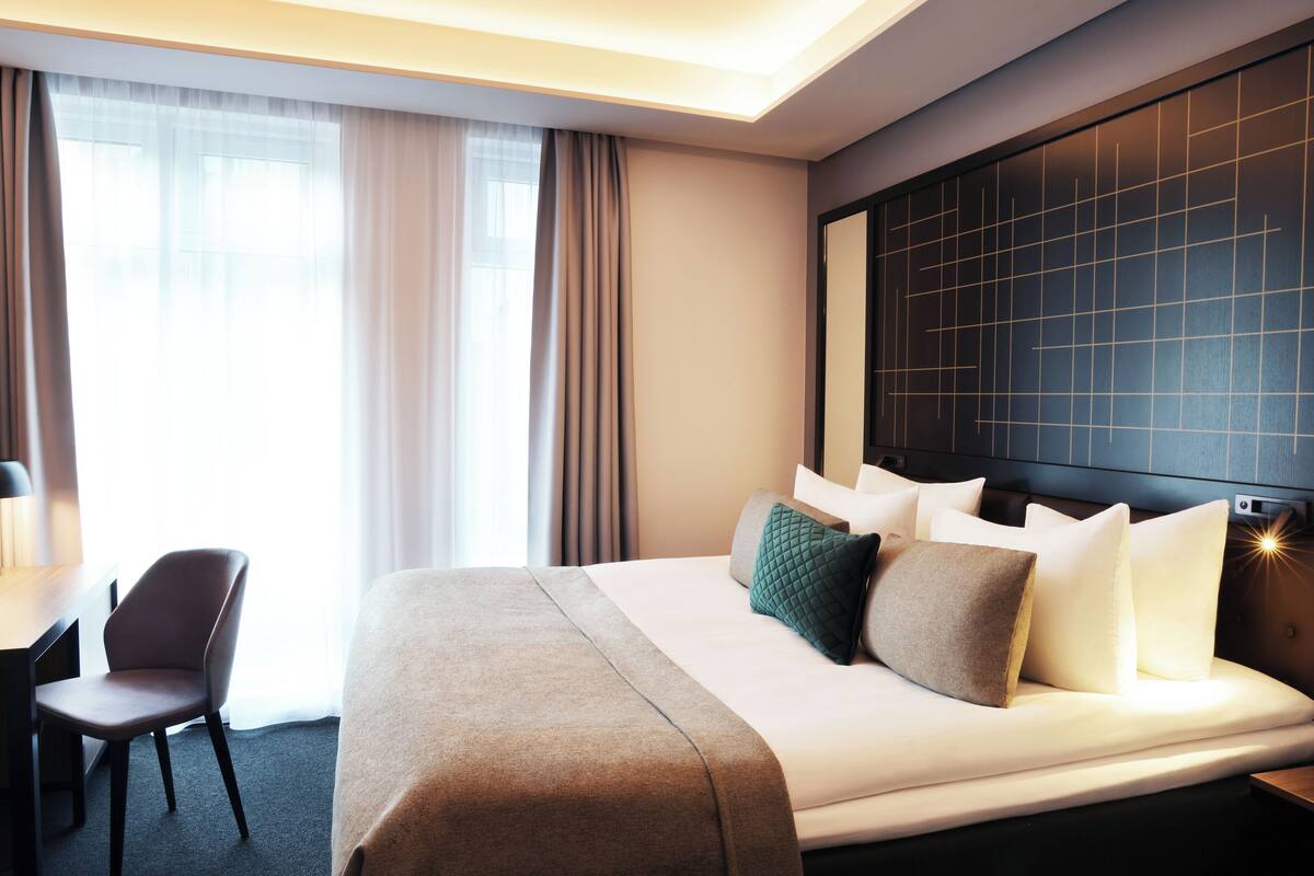 A hotel room with a large bed, a desk, and a chair.