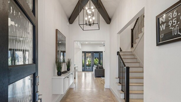 A spacious hallway with a wooden floor, a modern staircase with black railings, and a ceiling light fixture. - Gathering Place Luxury-Pool/Spa/OutdoorKitchen (Tulsa)