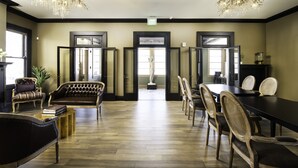 A spacious room with a large wooden table, several chairs, a sofa, and two chandeliers. - The Edward Hotel (Buffalo)