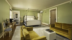 A bedroom with a four-poster bed, a yellow sofa, a white coffee table, and a desk with a chair. - The Edward Hotel (Buffalo)