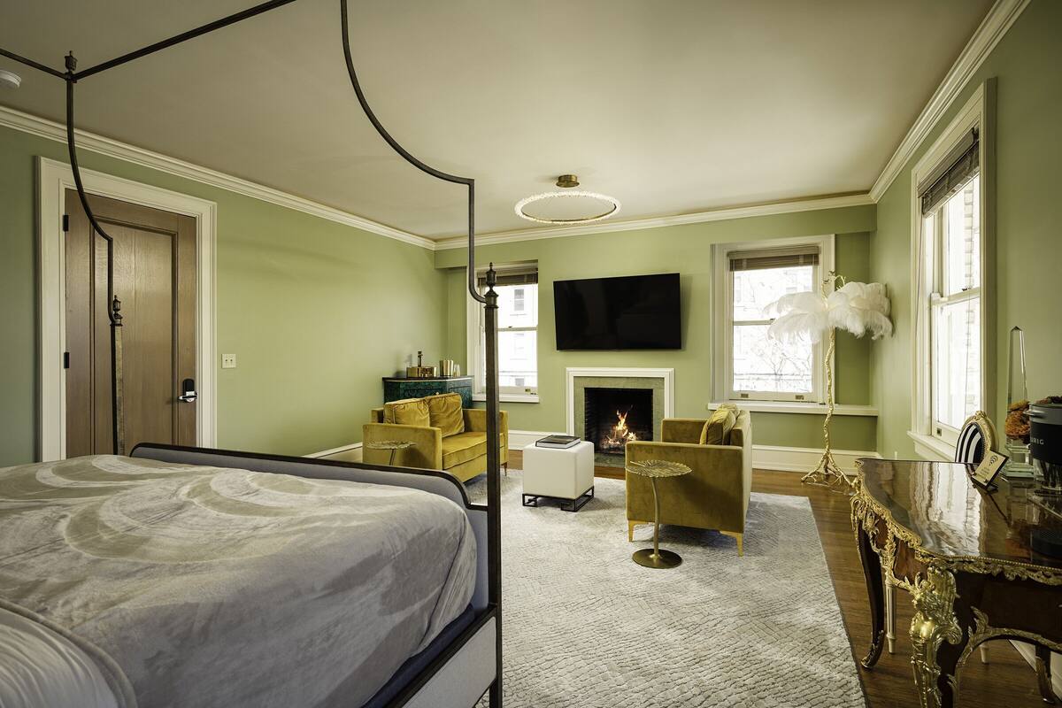 Un dormitorio con una cama con dosel, chimenea, televisor y comedor con mesa y sillas.