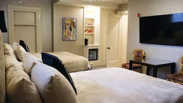 Una habitación de hotel con dos camas, un televisor, un cuadro y una pequeña mesa con sillas.