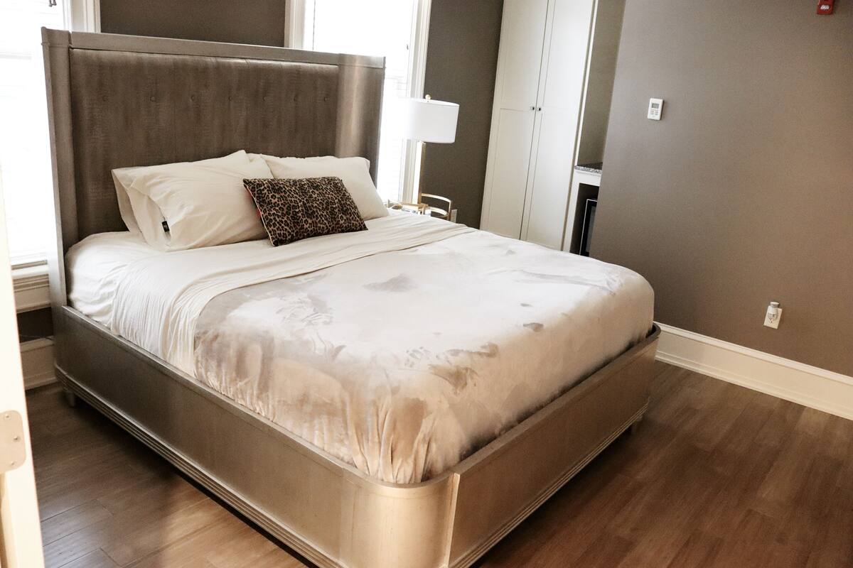 Un dormitorio moderno con una cama grande, una mesita de noche, una lámpara y un armario.