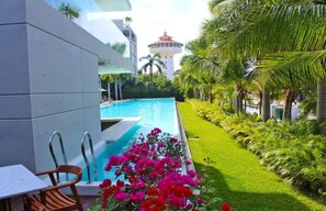 Una piscina con vistas a una torre, rodeada de abundante vegetación y palmeras.