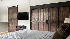 Une chambre à coucher avec un lit, une télévision et des armoires en bois.