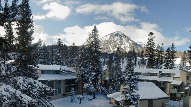 Une station de ski enneigée, avec des bâtiments, une piscine et une montagne en toile de fond.
