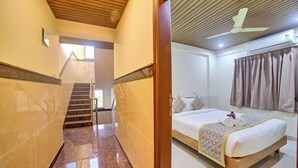 Una camera d'albergo con un letto, un bagno con doccia e una scala che conduce a un altro piano.