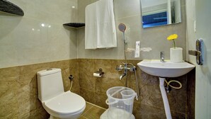 Un bagno con il water, un lavandino, uno specchio, un portasciugamani e un soffione.