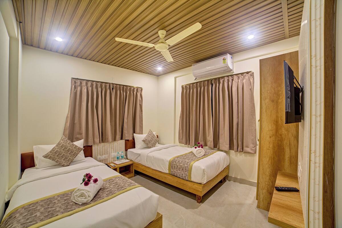 Une chambre d’hôtel avec deux lits, un ventilateur de plafond, un appareil de climatisation et un téléviseur.