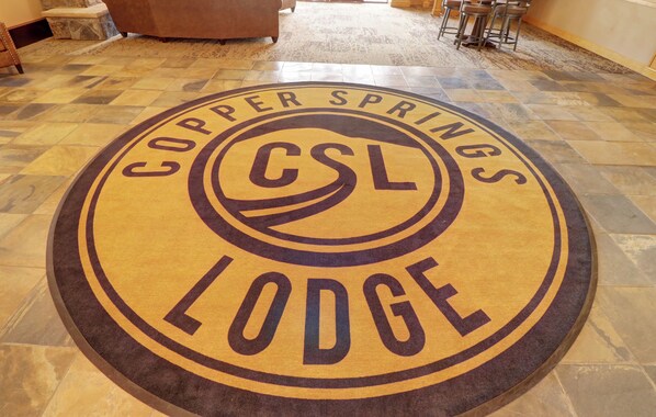 En rund logotyp på golvet med texten ”Copper Springs Lodge” och ”CSL”.