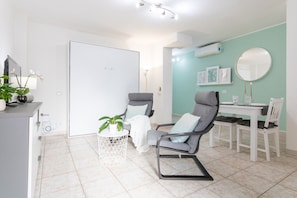 Relax in a comfortable seating area with a chair and small table, featuring a wall-mounted mirror and air conditioning unit.