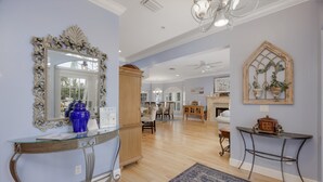 Un salón amplio con un espejo grande, un aparador de madera y un tapete azul.