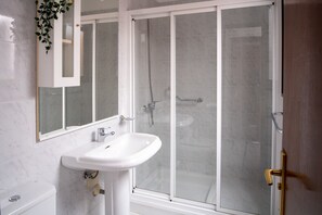 A bathroom with a white sink, a mirror, and a glass-enclosed shower area.