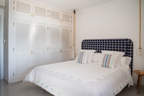 Une chambre à coucher avec un lit, une armoire blanche et une tête de lit à motifs géométriques.