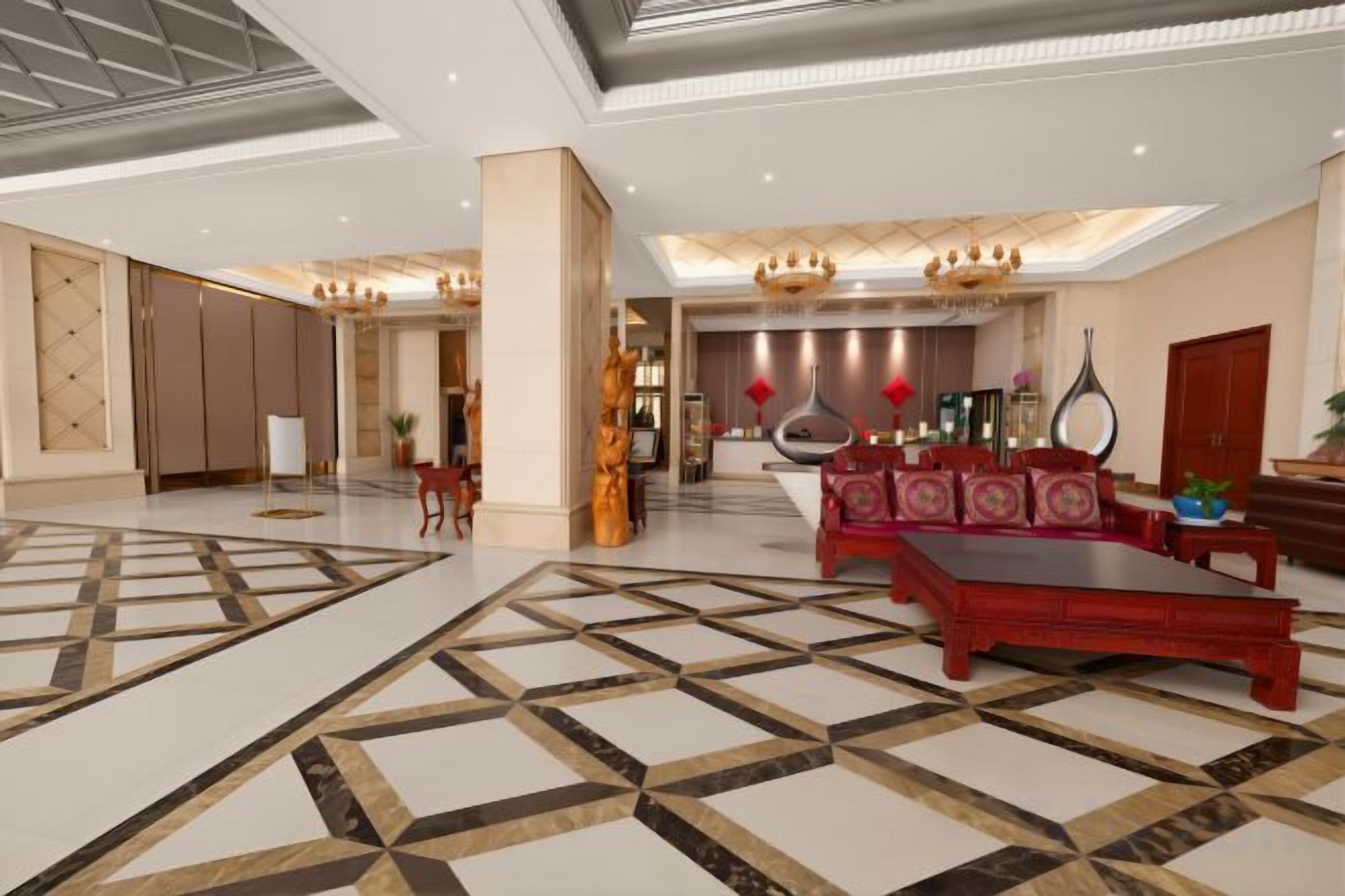 A spacious lobby with a large seating area, a reception desk, and a modern chandelier.
