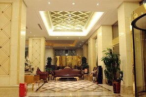 A spacious lobby with a high ceiling, a central seating area, and a large potted plant.