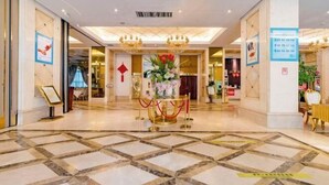Een hotel lobby met een marmeren vloer, een receptiebalie en een bloemstuk.