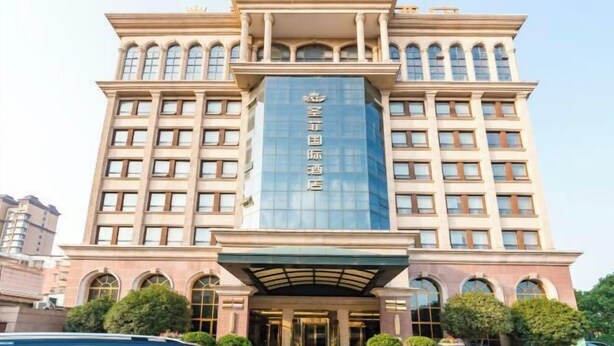 Een hotel met meerdere verdiepingen, een opvallende ingang, grote ramen en een centraal verticaal bord.