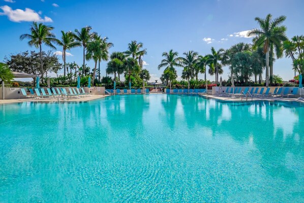 Relax by the pool surrounded by palm trees and lounge chairs.