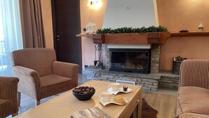 Un accogliente soggiorno con poltrone a righe, un tavolino in legno con un libro, un camino e una cornice in pietra.