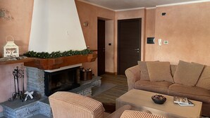 Un accogliente soggiorno con camino, arredi a righe e una porta che dà su un'altra stanza.