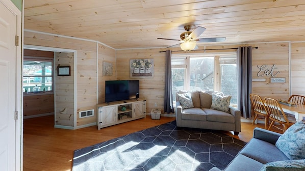 A cozy living room with a television, sofa, and dining area.