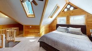 A bedroom with a sloped ceiling, wooden walls, a bed with pillows, a nightstand, and a small staircase. - Luxury Cottage in Nelsonville, close to Train, Opera House, near Hocking Hills (Nelsonville)