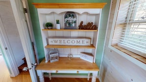 Un'unità scaffale in legno con un cartello che riporta la scritta 'WELCOME', un cartello con la scritta 'hello' e una piccola pianta in vaso.