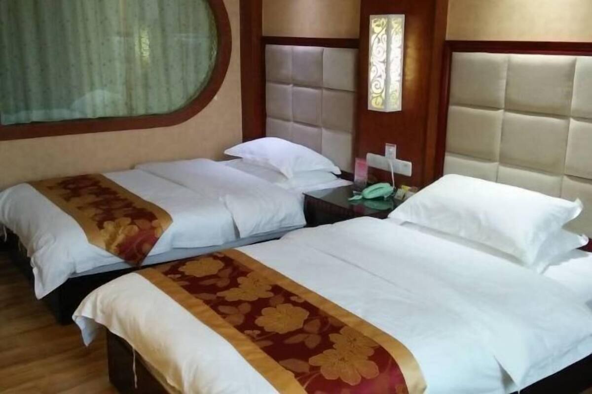 A hotel room with two beds, each with a headboard and a bedside table.