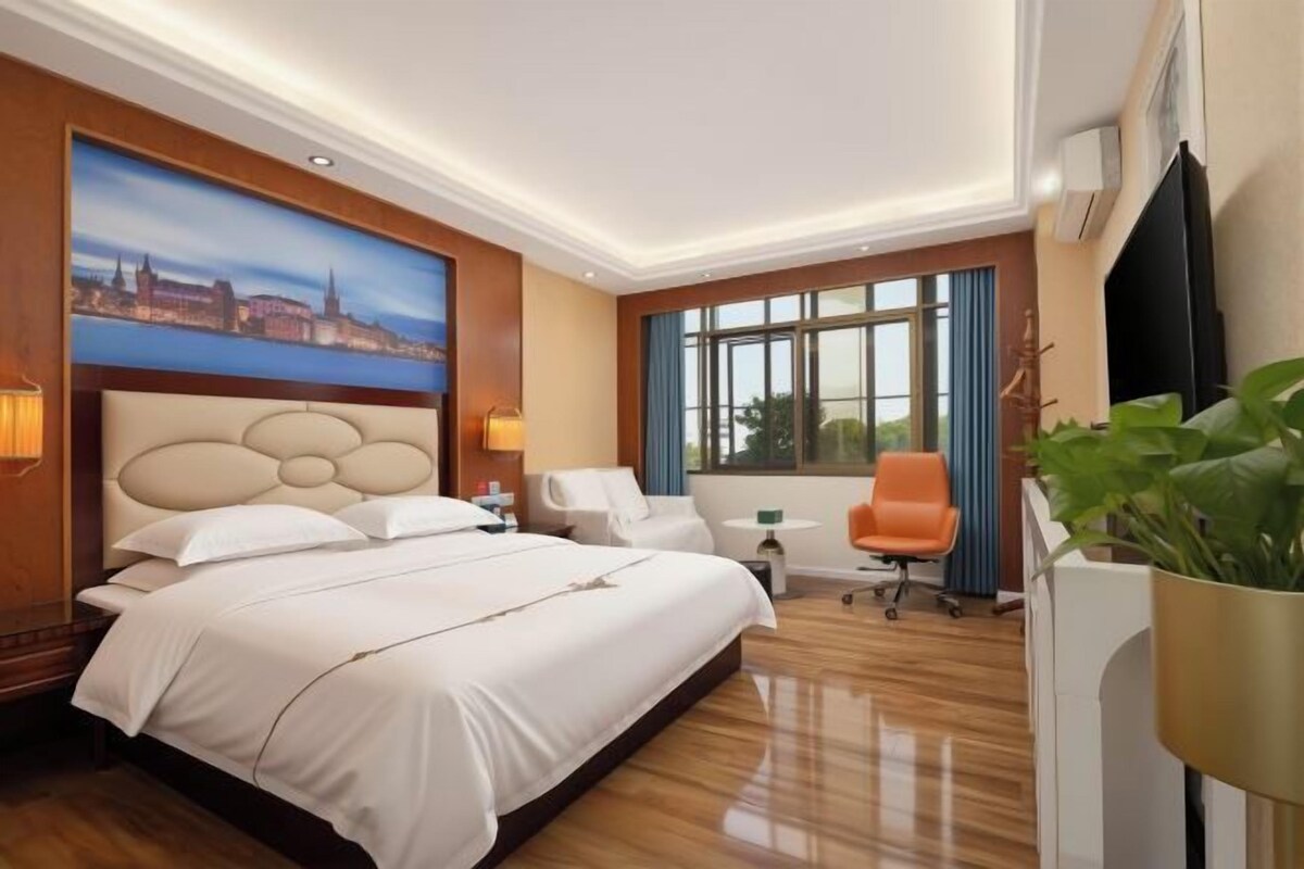 Una habitación de hotel con una cama grande, un escritorio, una silla y un televisor.
