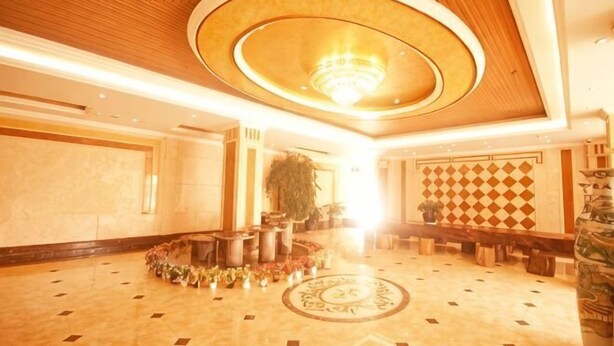 A spacious lobby with a circular seating area, a chandelier, and a patterned wall. - Feicui Hotel (Mangshi)