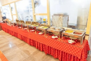 A buffet setup with multiple food stations and a checkered tablecloth. - Feicui Hotel (Mangshi)