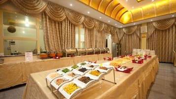Montaje tipo buffet con varias estaciones de comida y una mesa larga.
