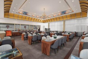 A spacious conference room with tables and chairs, a large chandelier, and a modern ceiling design. - Feicui Hotel (Mangshi)